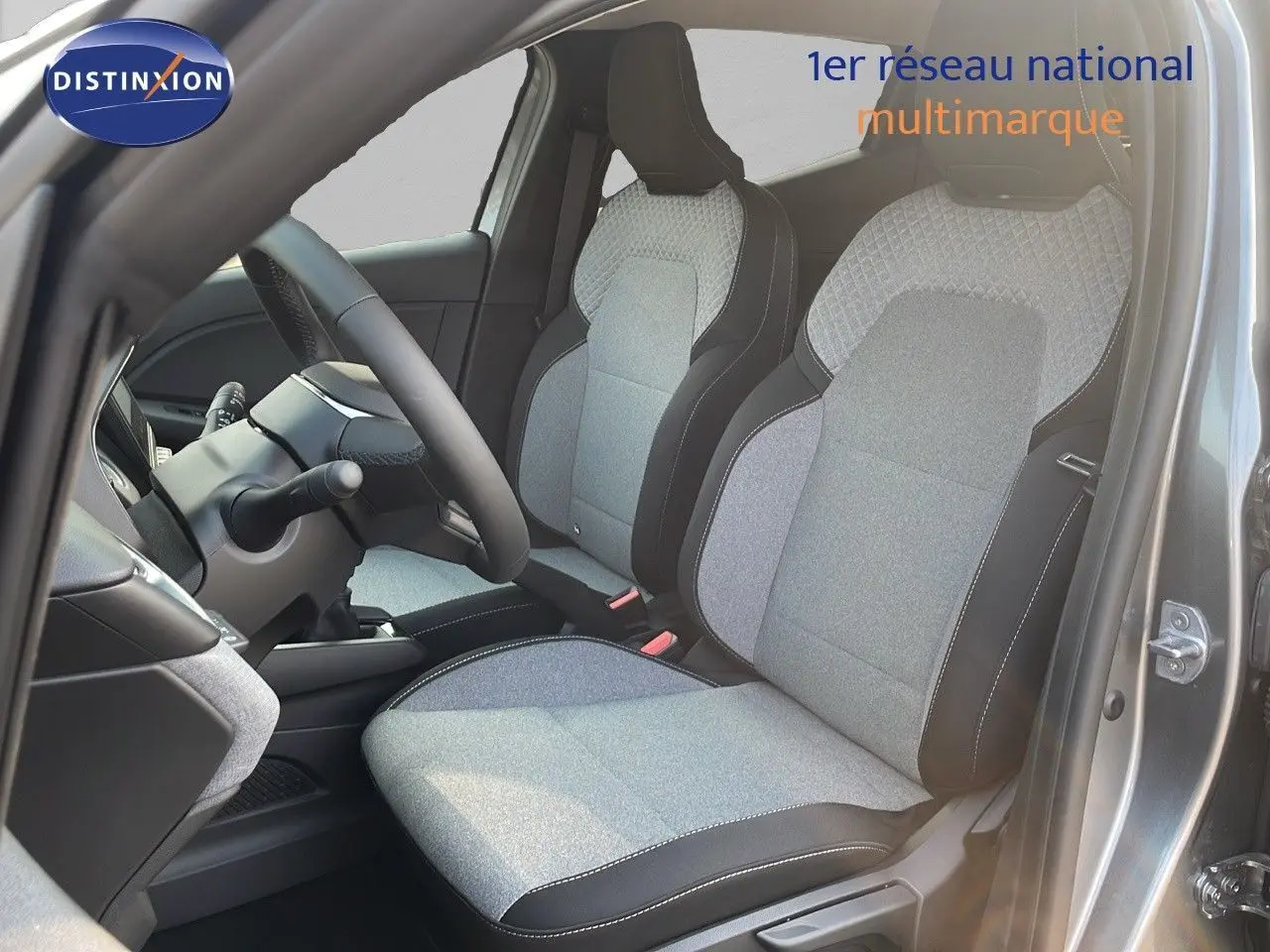 Intérieur de la Renault Clio 1.5 DCI 2025, vue côté conducteur, sièges tissu gris clair avec surpiqûres blanches.