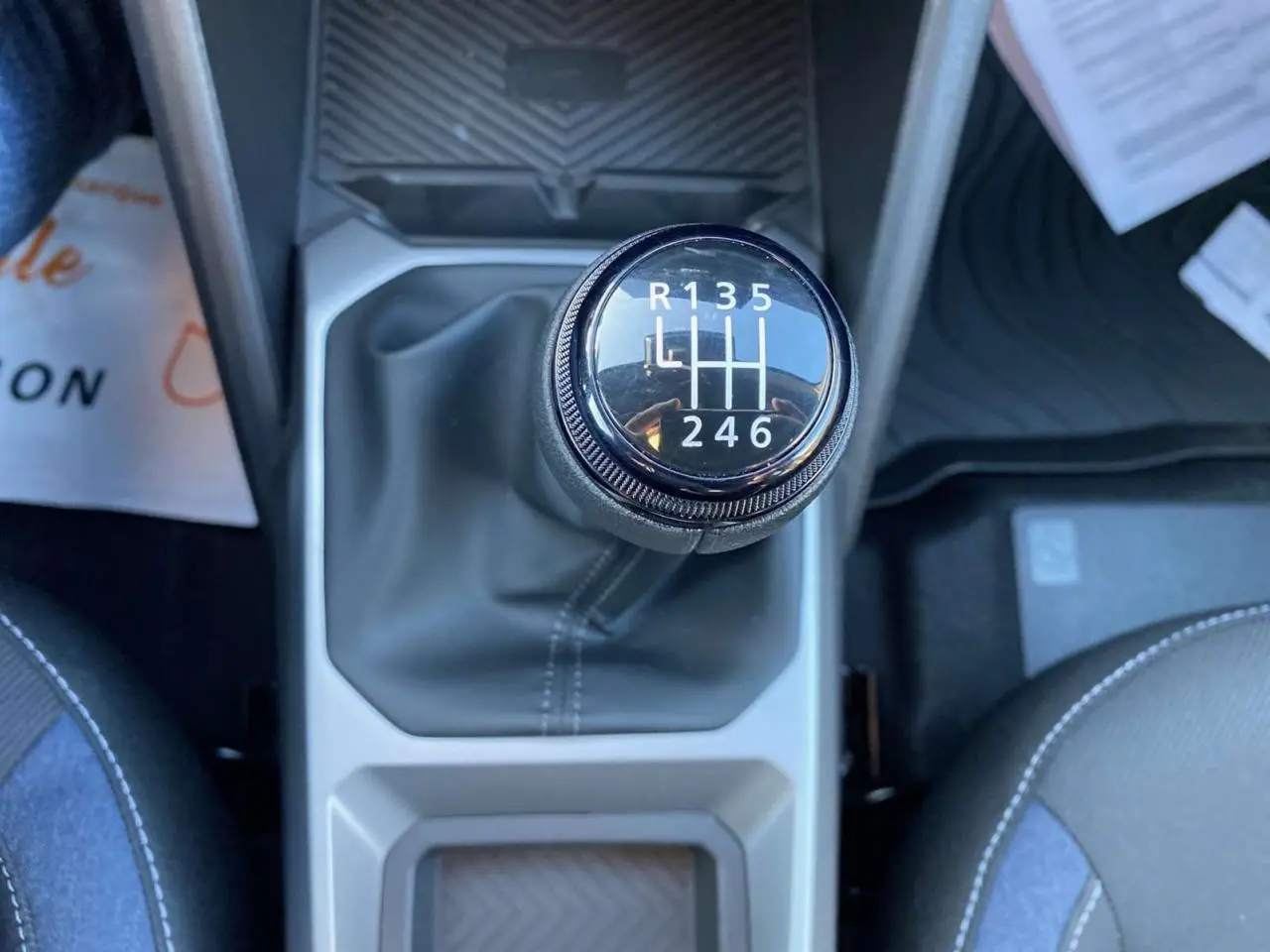 Le levier de vitesses manuel du Dacia Duster 2024 vu de dessus, entouré de sièges gris et bleu.