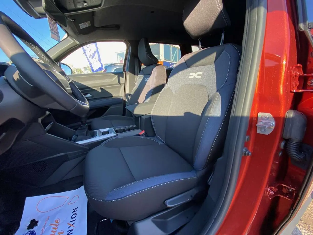 Vue intérieure côté conducteur du Dacia Duster 2024 brun terracotta, mettant en valeur les sièges tissu avec logo Extreme.