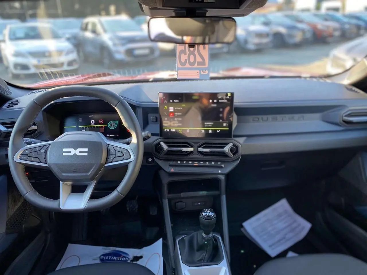 Vue intérieure avant du tableau de bord du Dacia Duster 2024 avec volant multifonction et écran tactile central.