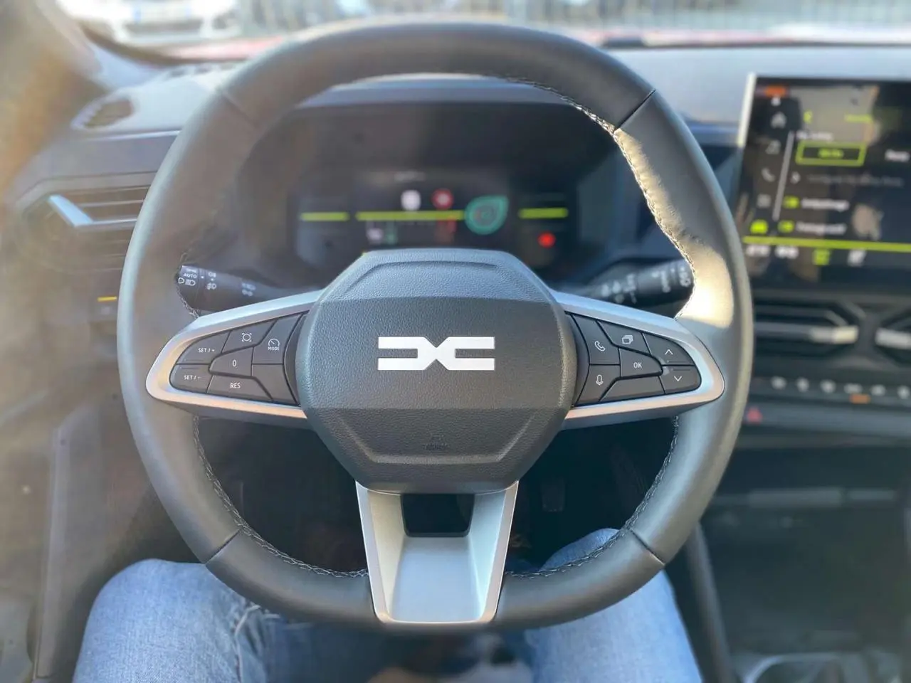 Volant multifonction du Dacia Duster 2024 vu de face, avec tableau de bord digital et écran central en arrière-plan.