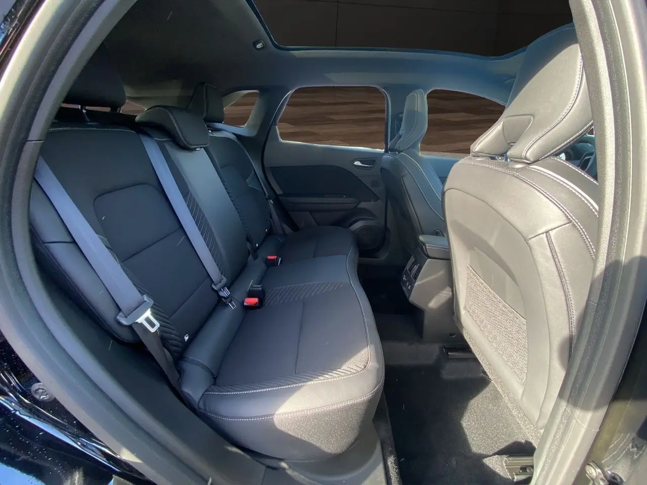 Vue intérieure côté droit sur la banquette arrière noire étoile du Renault Symbioz Iconic E-Tech Hybrid 2025 avec toit panoramique.