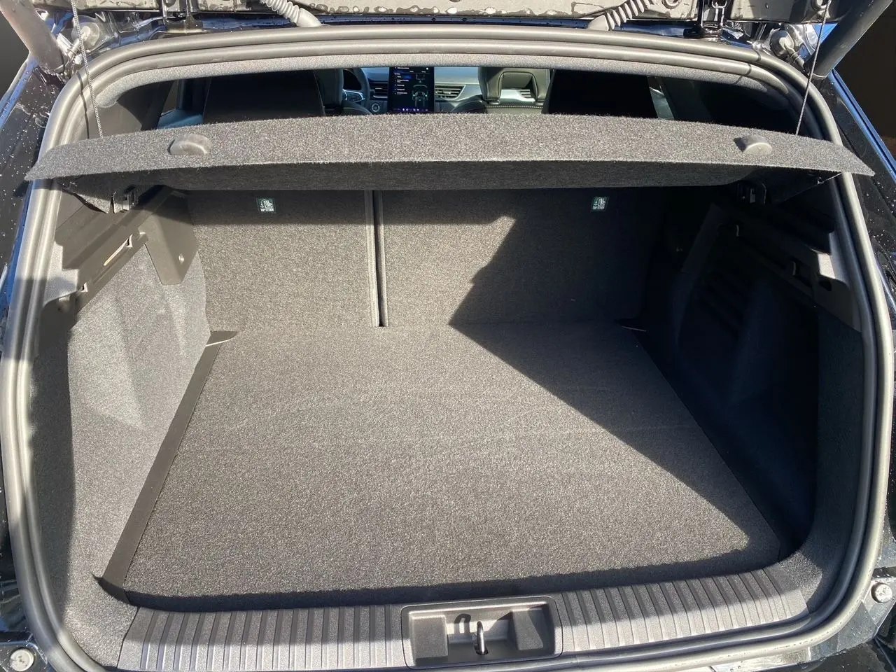 Coffre ouvert vu de l'arrière d'une Renault Symbioz noir étoile, montrant l'espace de chargement et la tablette cache-bagages.