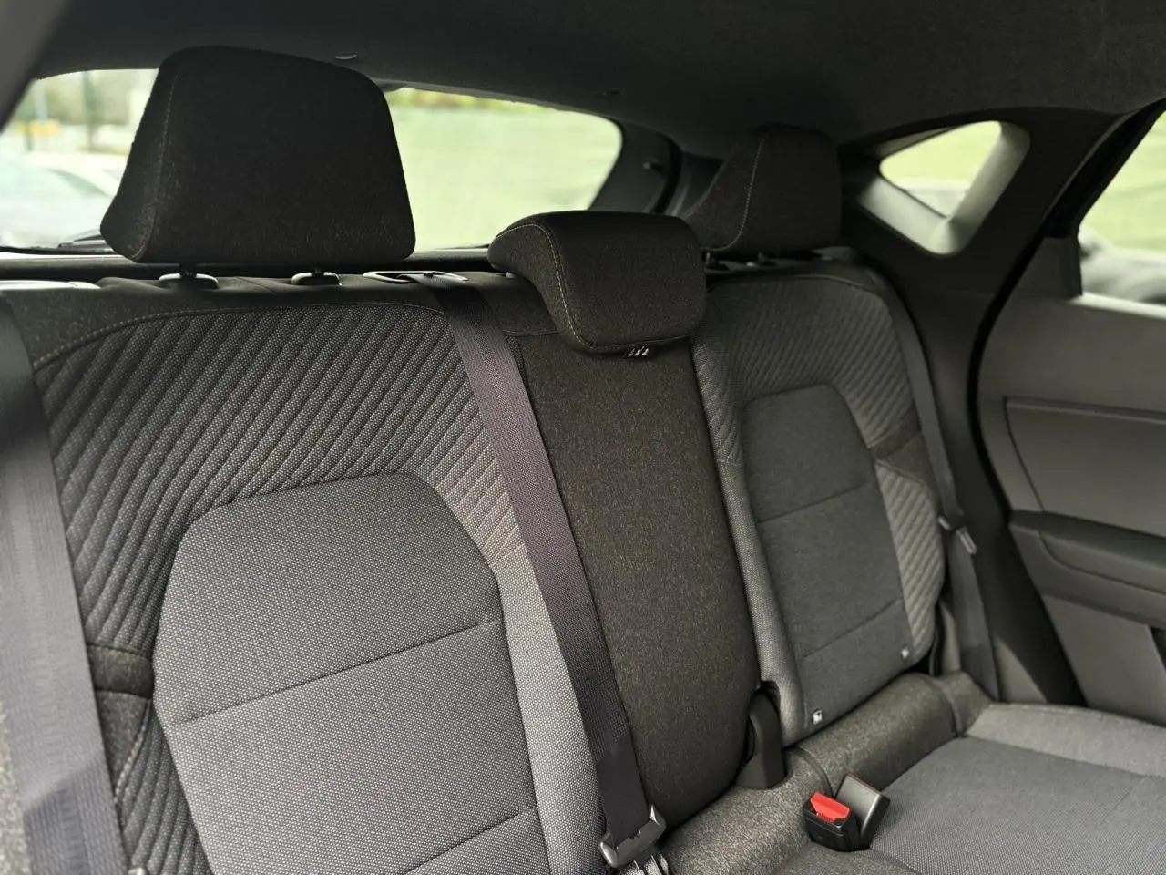 Vue intérieure sur la banquette arrière grise du Renault Captur 2025, avec ceintures de sécurité et appuie-têtes visibles.