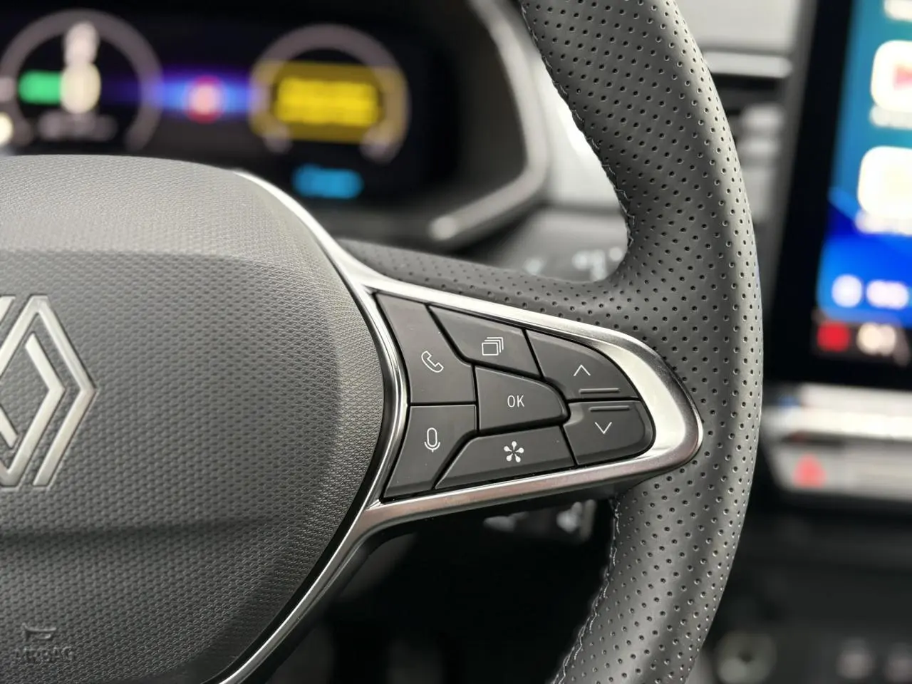 Gros plan sur le volant en cuir perforé du Renault Captur noir étoile, avec commandes multifonctions visibles.