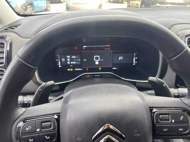 Vue depuis le siège conducteur sur le volant cuir et le tableau de bord numérique du Citroën C5 Aircross blanc Banquise.