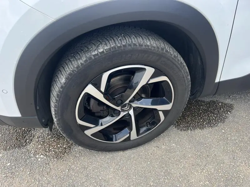 Gros plan sur la roue avant gauche du Citroën C5 Aircross blanc Banquise avec jante alliage noire et argentée.