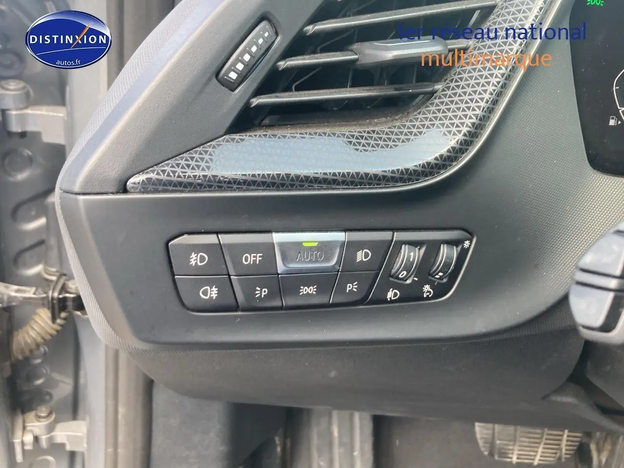 Détail des commandes d'éclairage intérieures sur la gauche du tableau de bord de la BMW Série 1 gris foncé 2023.