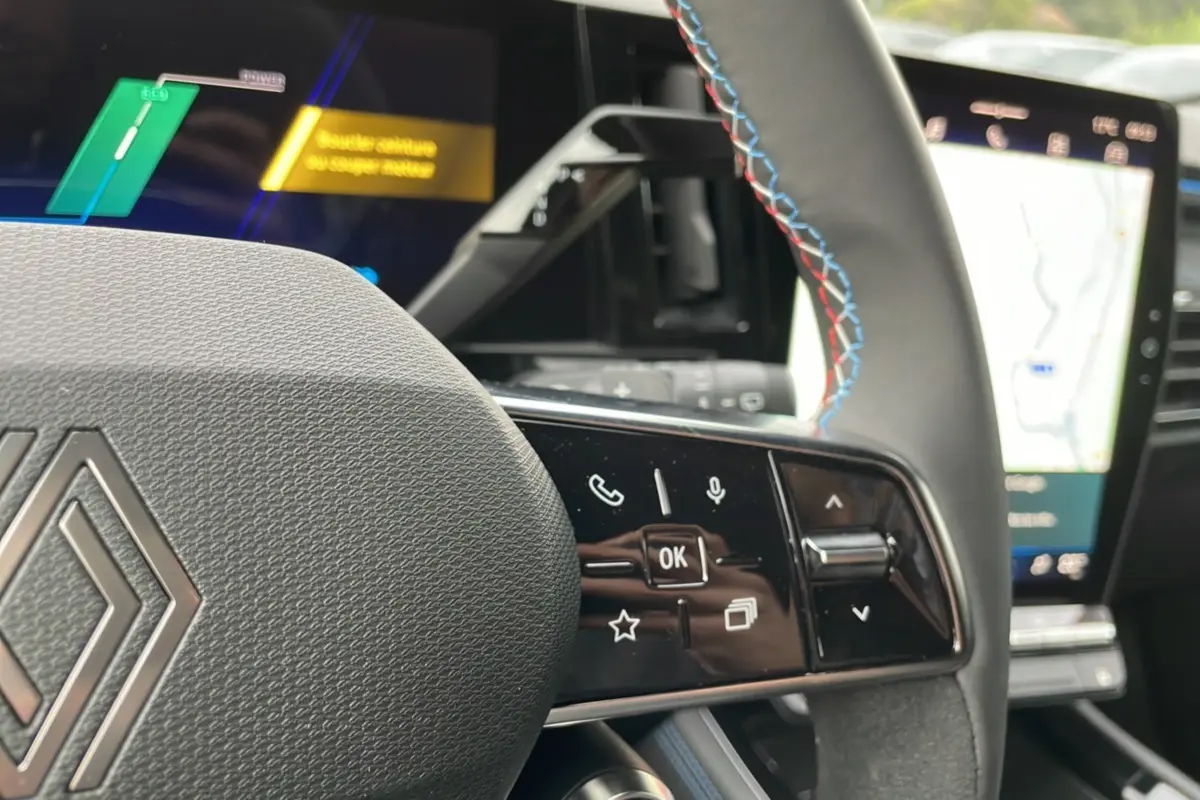 Vue rapprochée du volant du Renault Austral New 200 Esprit Alpine bleu outremer, avec commandes multifonctions et coutures tricolores.