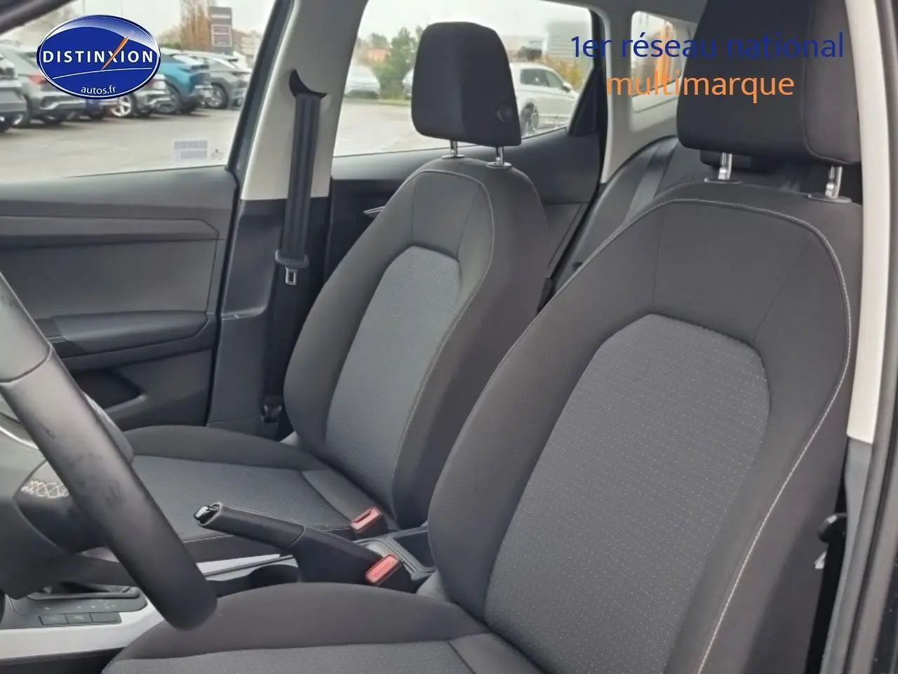 Vue intérieure côté avant droit montrant les sièges tissu gris et le levier de frein à main d'une SEAT Arona 2025.