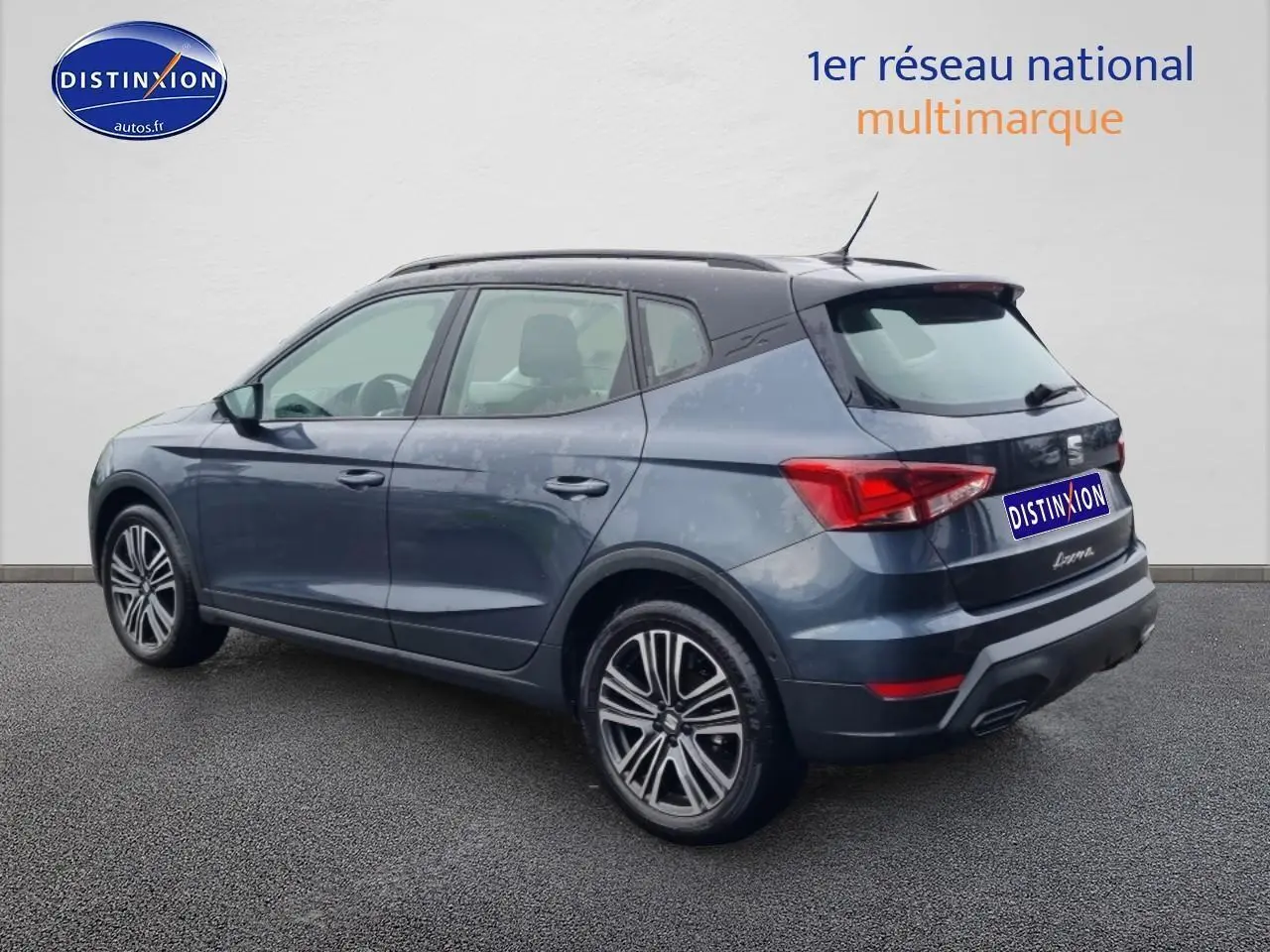 Vue 3/4 arrière droite d'un SEAT Arona gris magnétique avec jantes 17 pouces et barres de toit noires.