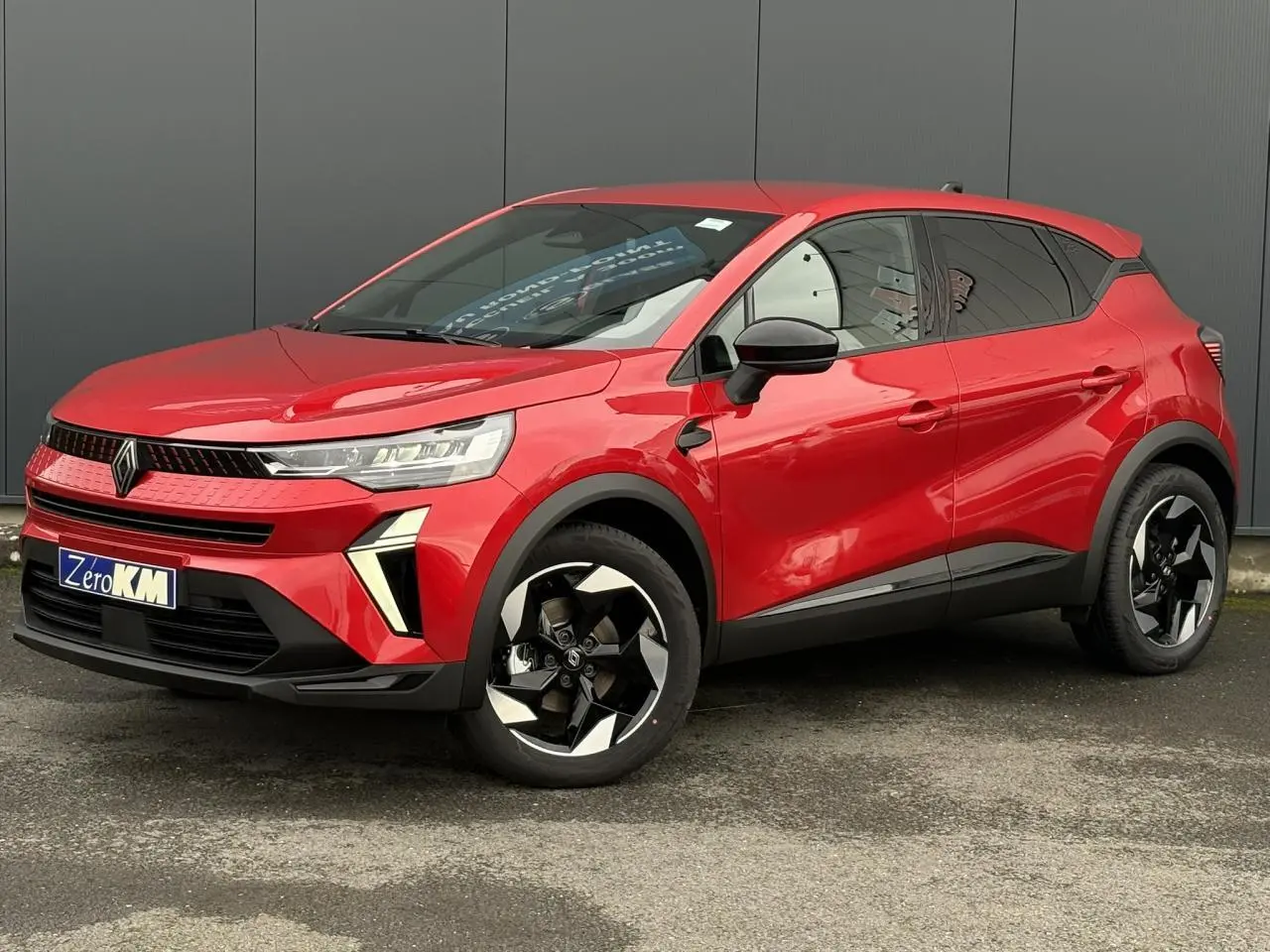 Renault Captur rouge flamme en 3/4 avant droit avec jantes aluminium noires et détails noirs brillants.