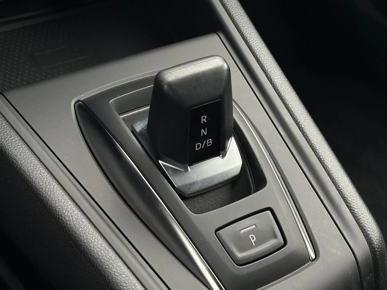 Gros plan sur la commande de boîte automatique noire du Renault Captur 2025, avec bouton de parking intégré.