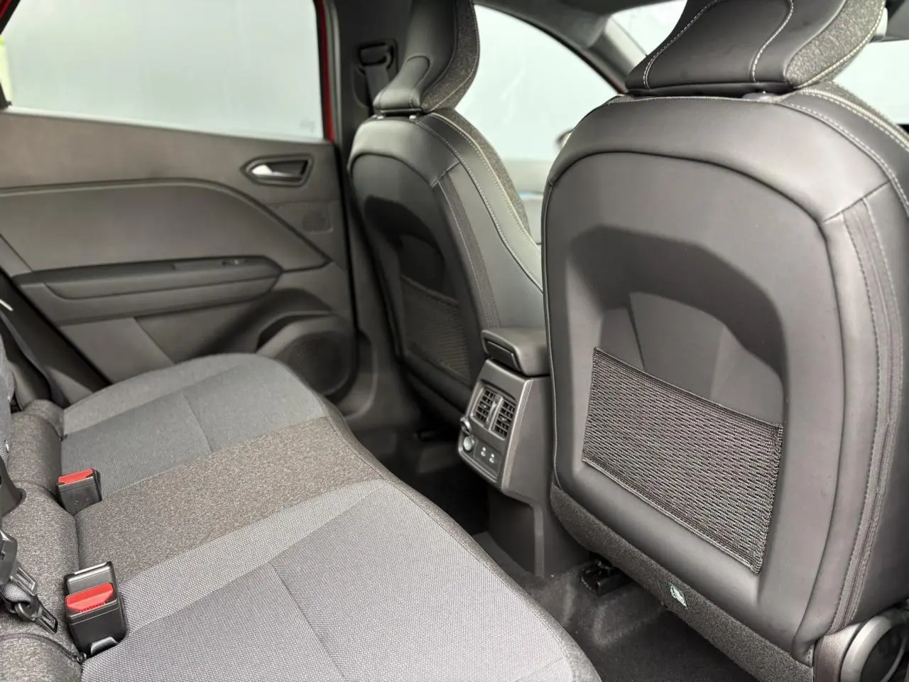 Vue arrière intérieure du Renault Captur 2025, montrant les sièges arrière gris et les aérations centrales.