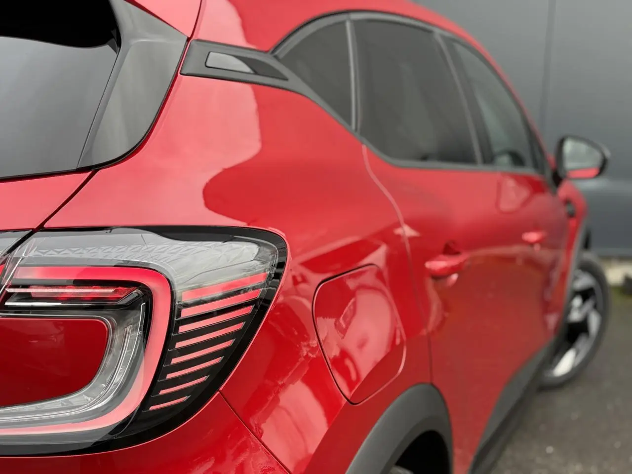 Vue 3/4 arrière droite du Renault Captur rouge Flamme avec feux arrière LED et jantes aluminium noires.