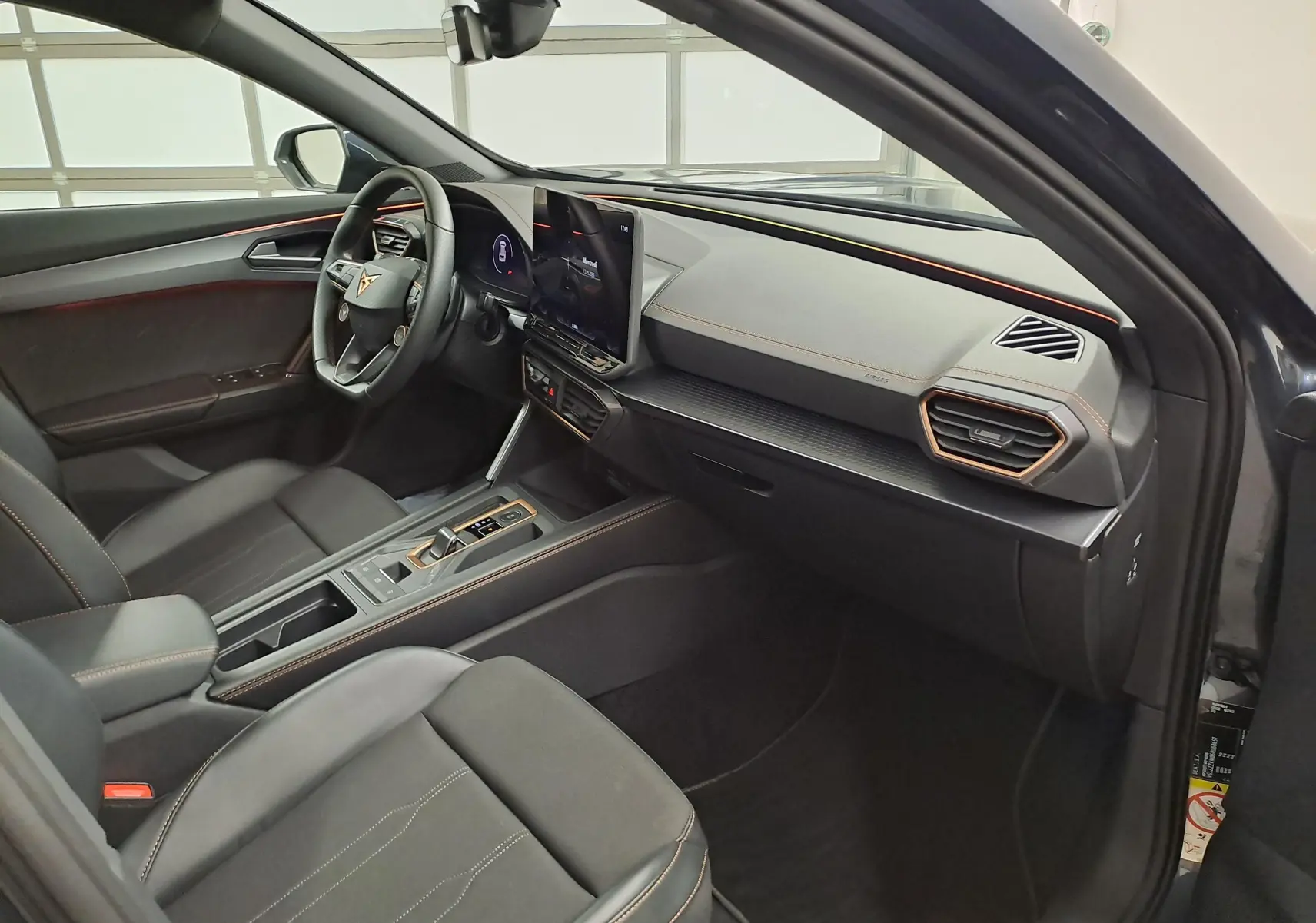 Vue intérieure côté conducteur du CUPRA Formentor 2025 avec tableau de bord noir et inserts cuivrés, volant cuir et écran tactile central.