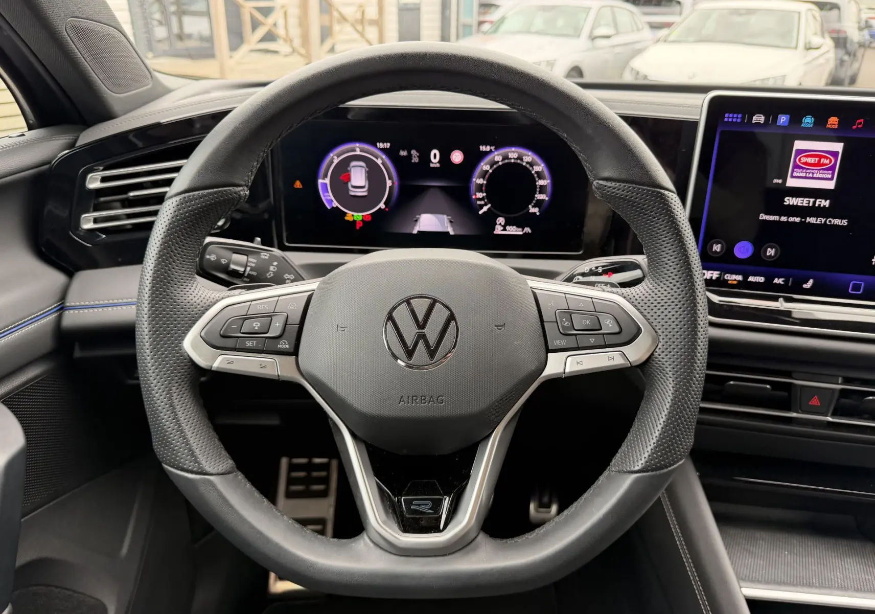 Vue intérieure centrée sur le volant cuir noir du Volkswagen Tiguan 2025 avec tableau de bord numérique et écran tactile.