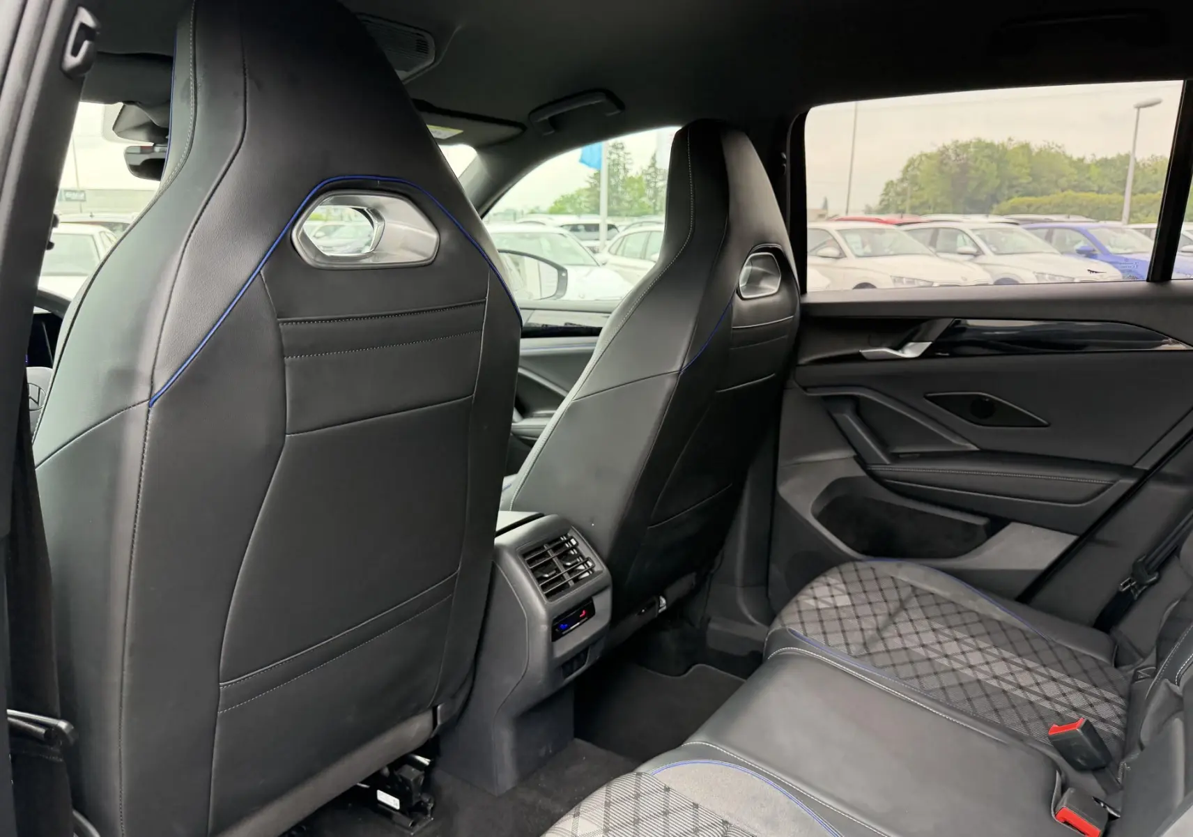 Vue intérieure arrière du Volkswagen Tiguan gris, sièges avant sport noirs avec surpiqûres bleues et banquette arrière en tissu et cuir.
