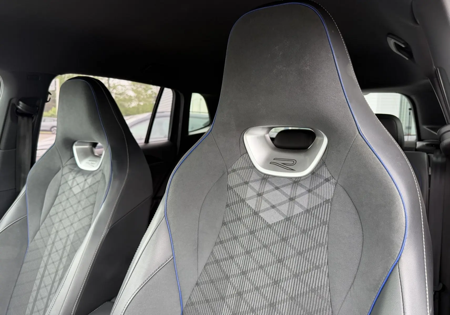Gros plan sur les sièges avant sport gris avec surpiqûres bleues du Volkswagen Tiguan 2025 version R-Line.