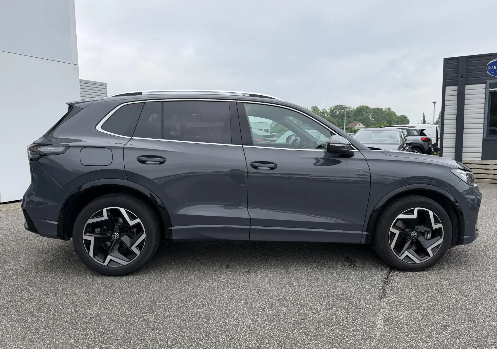 Vue de profil côté gauche d’un Volkswagen Tiguan gris métallisé 2025 avec jantes alliage 19 pouces et pack R-Line extérieur.