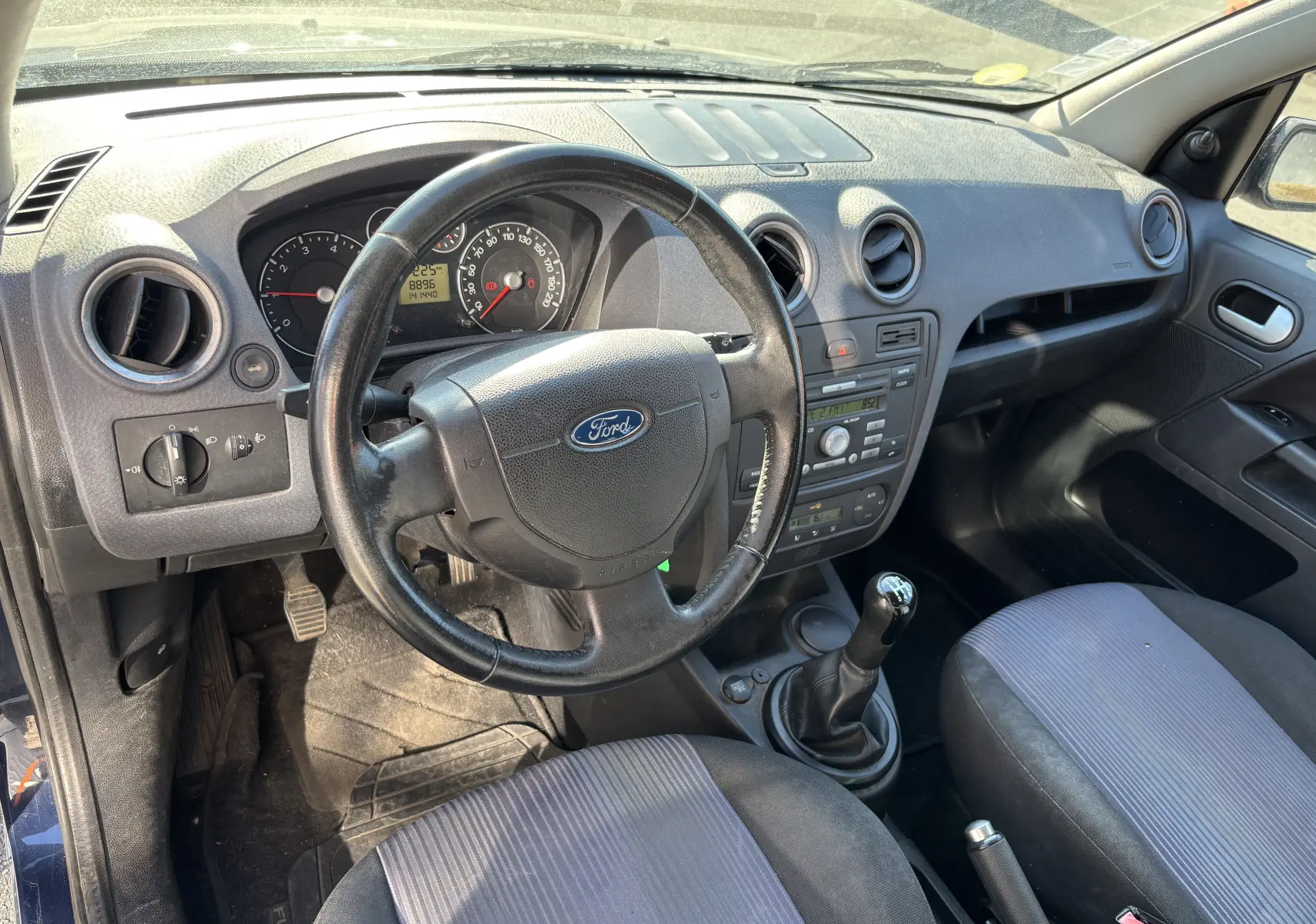 Vue intérieure côté conducteur de la Ford Fusion 2009 bleu, montrant le volant, tableau de bord et levier de vitesses manuel.