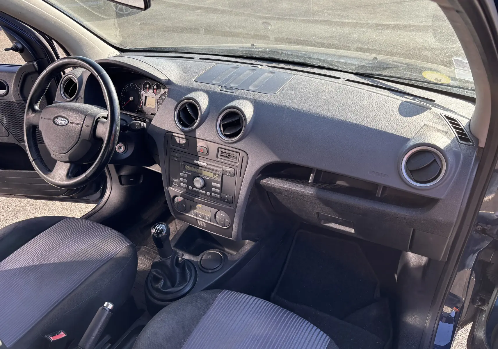 Vue intérieure côté conducteur de la Ford Fusion 2009 avec tableau de bord noir et levier de vitesse manuel.