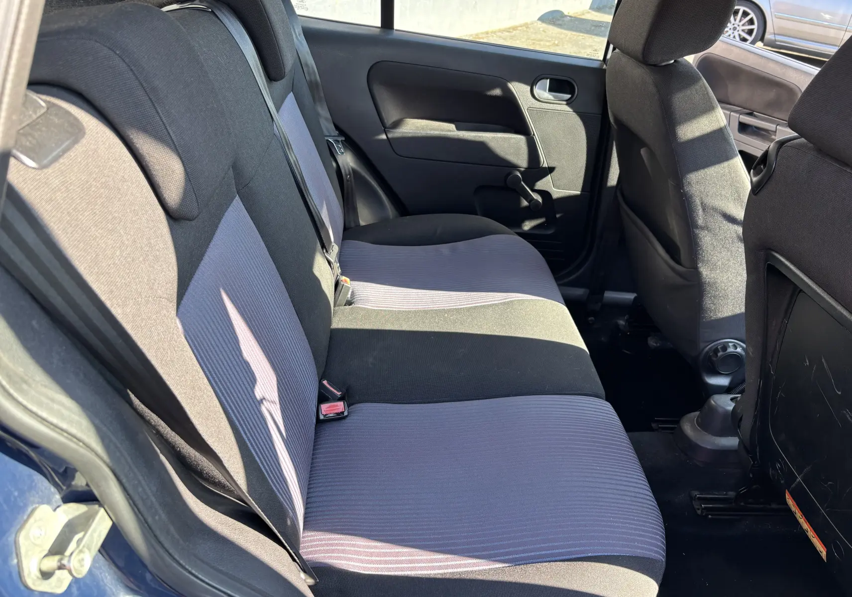 Vue intérieure arrière gauche des sièges arrière bi-ton gris et noir d'une Ford Fusion 2009 bleue avec porte ouverte.