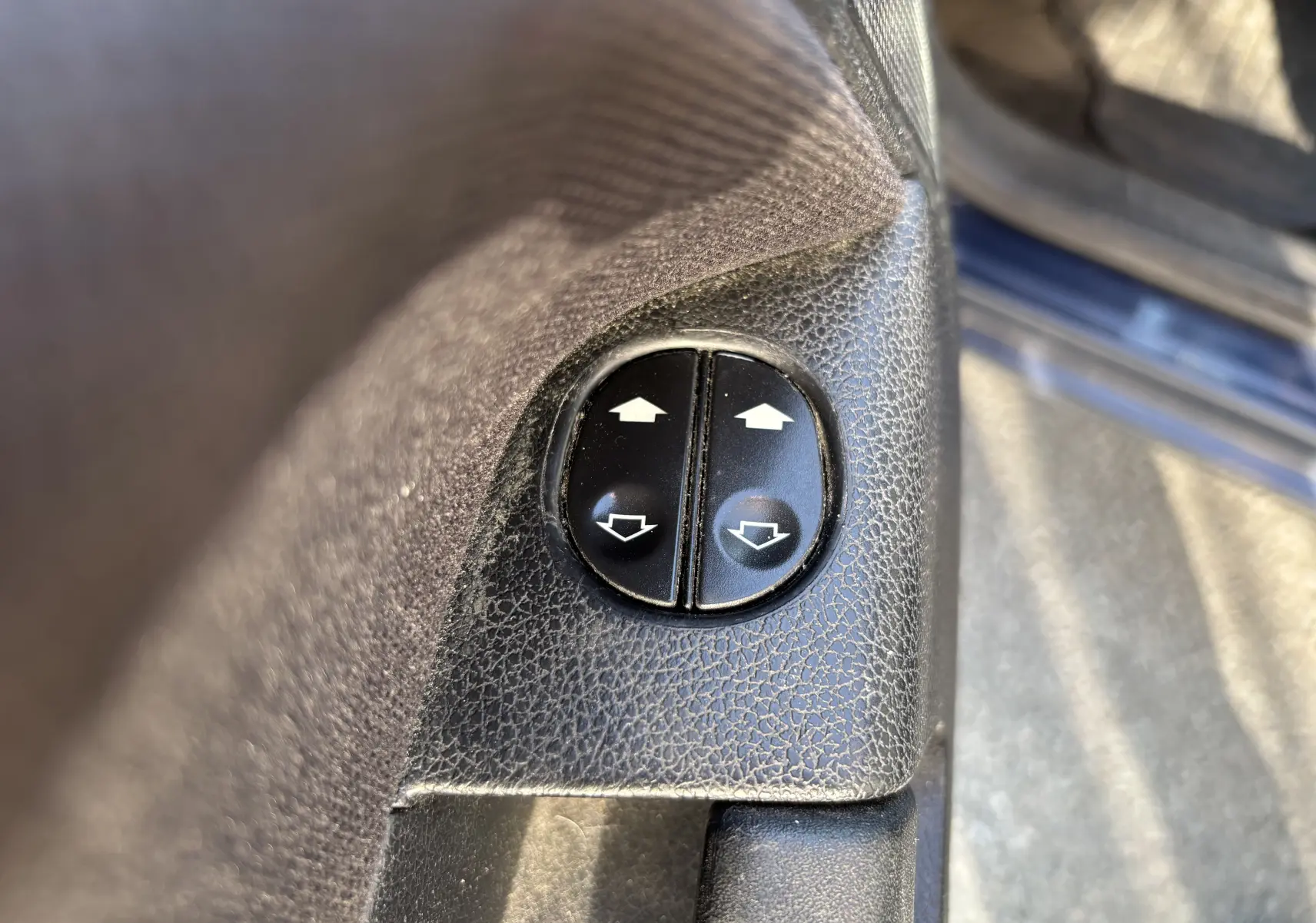 Boutons de commande des vitres électriques sur la porte intérieure côté gauche d'une Ford Fusion bleu 2009.