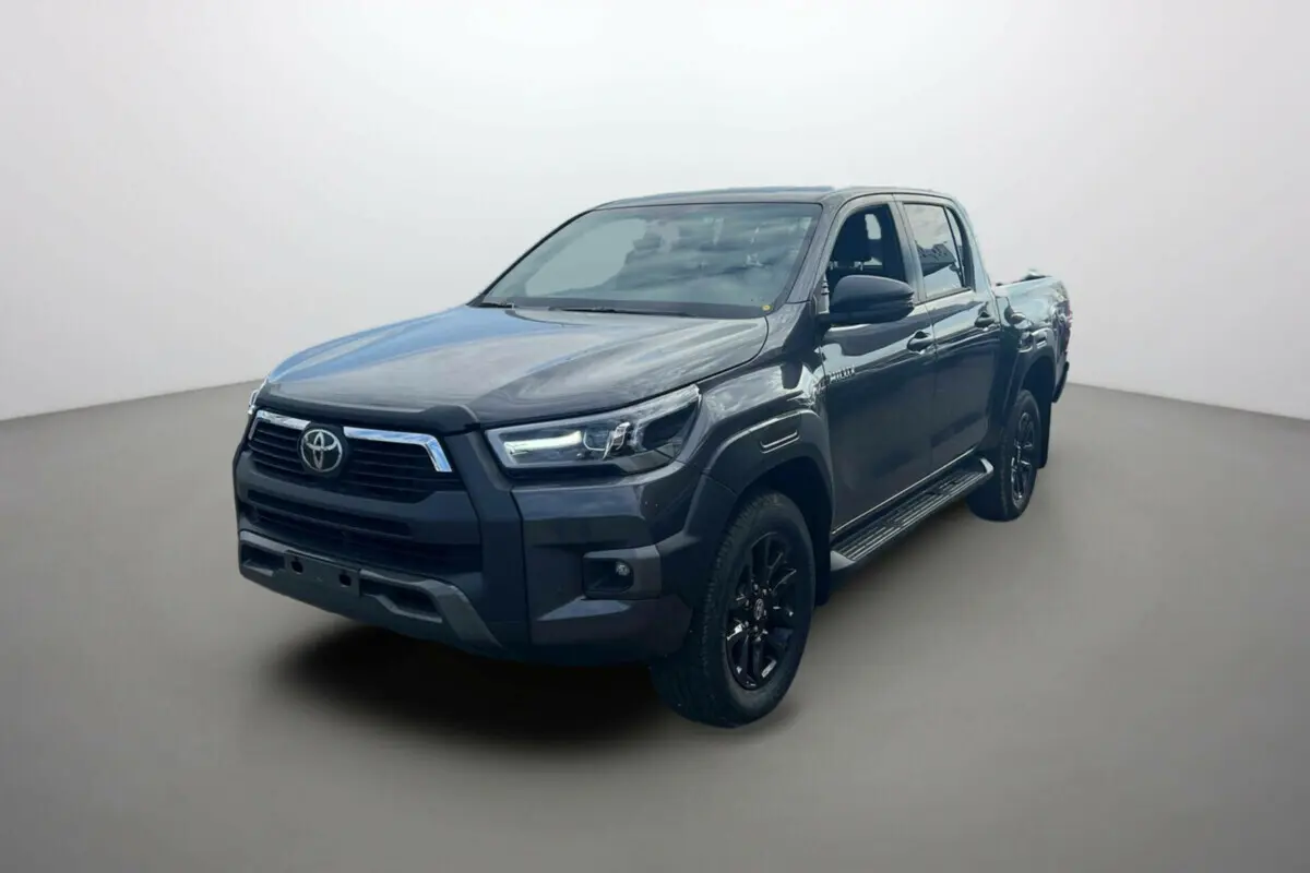Toyota Hilux 4x4 gris atlas en 3/4 avant droit, avec jantes noires et calandre imposante, modèle 2025 Invincible.