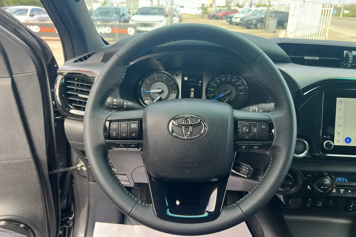 Vue centrée sur le volant du Toyota Hilux 2025 gris atlas, montrant commandes intégrées et tableau de bord numérique.