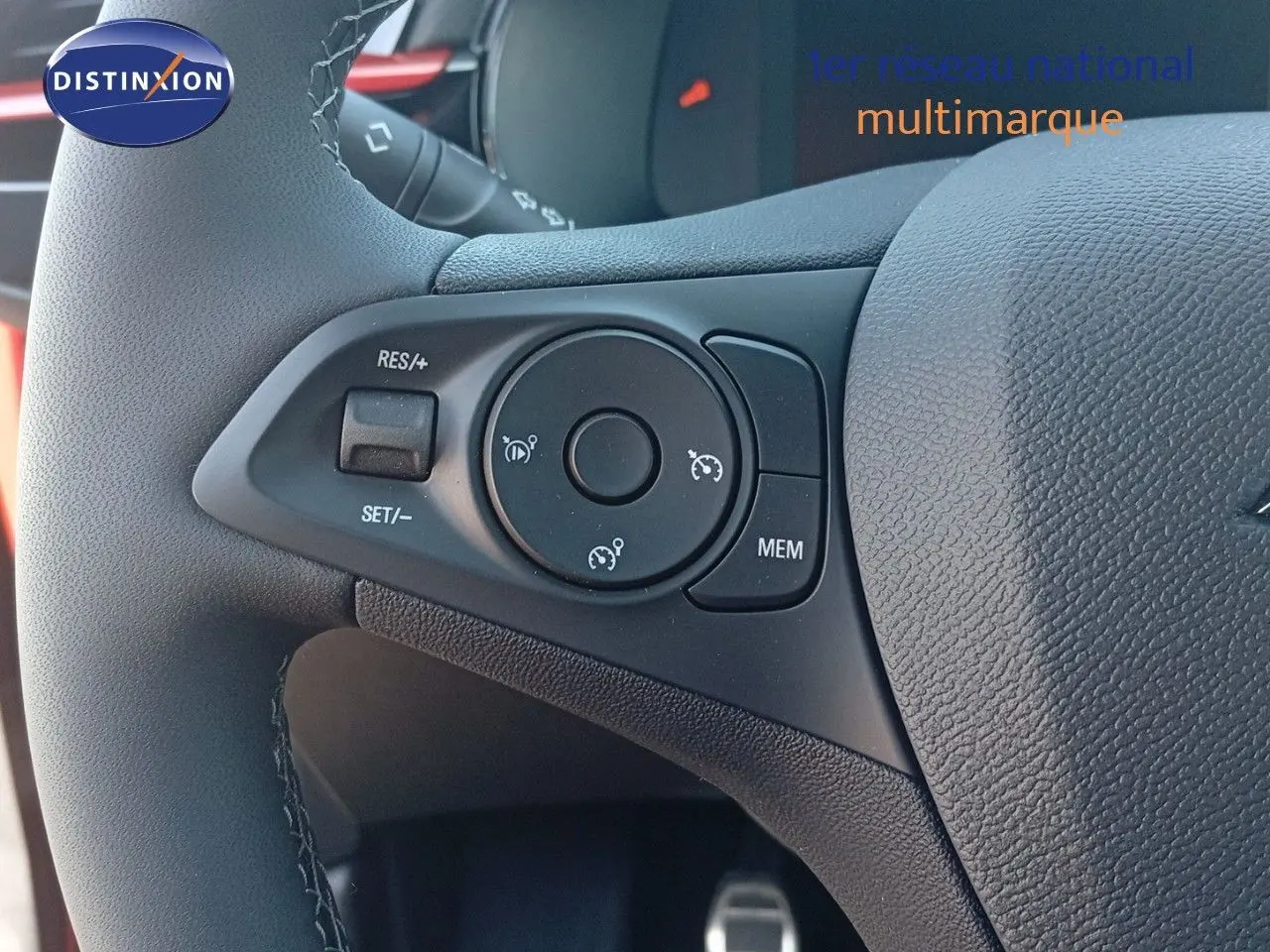 Gros plan sur les commandes de régulateur de vitesse au volant d'une Opel Corsa rouge métal 2023.