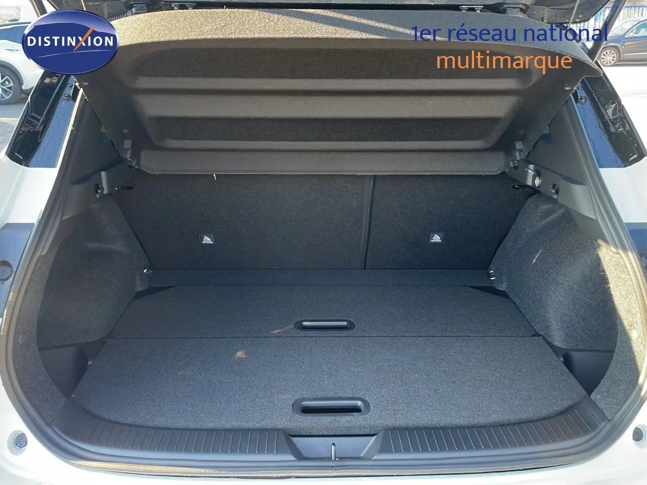 Coffre ouvert d'un Nissan Qashqai blanc nacré avec toit noir, vue arrière montrant l'espace de chargement plat et spacieux.