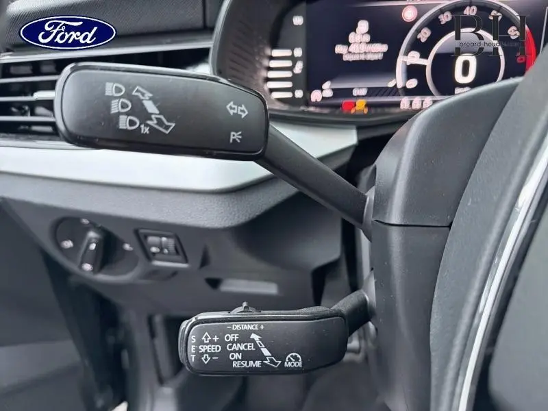 Gros plan sur les commandes au volant d'un Skoda Kamiq gris, affichage numérique du tableau de bord en arrière-plan.