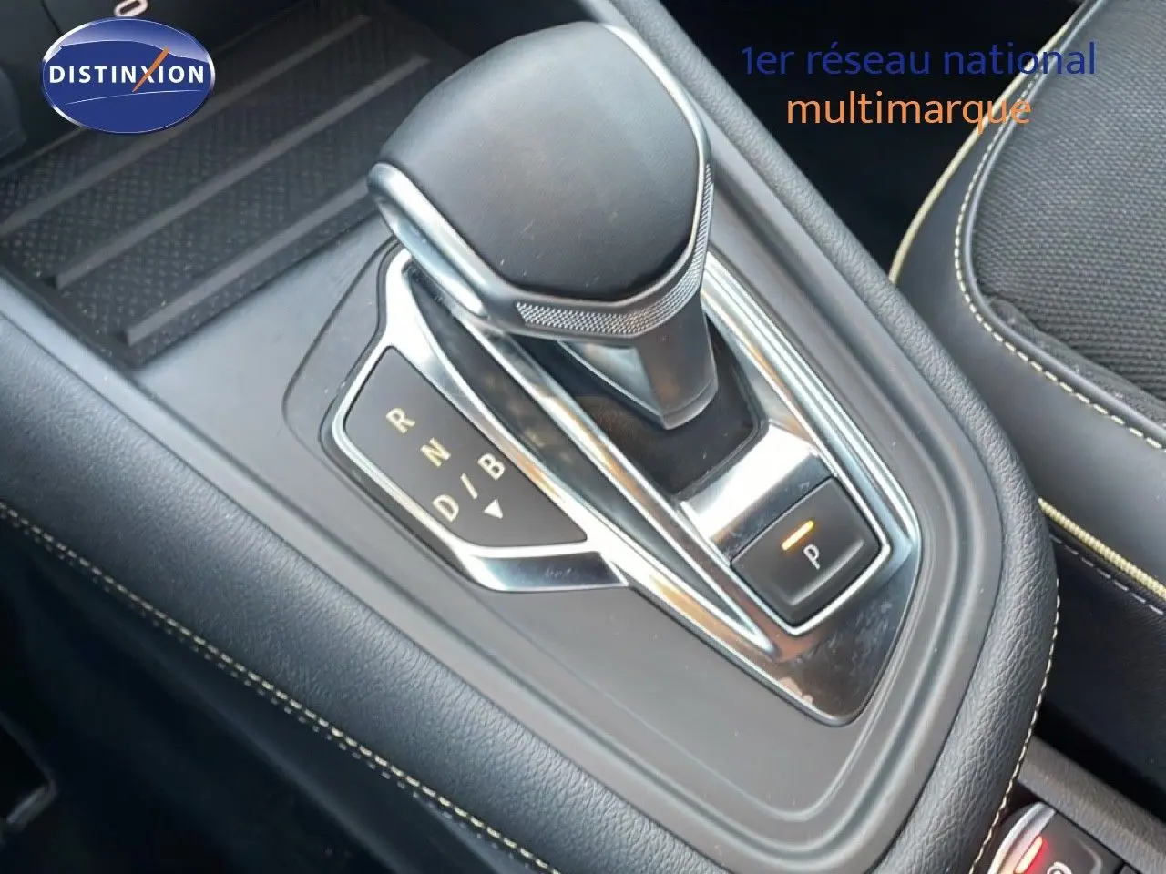 Gros plan sur la commande de boîte automatique noire avec surpiqûres beiges dans le Renault Symbioz gris cassiopée.