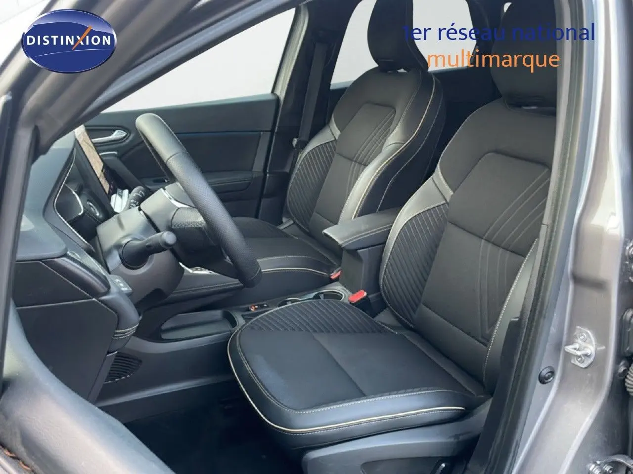 Vue intérieure côté conducteur de la Renault Symbioz gris cassiopée, sièges tissu noir avec surpiqûres claires.