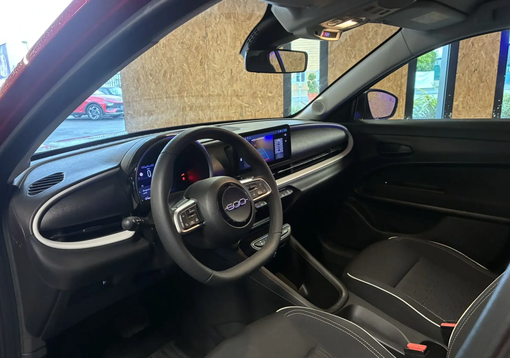 Intérieur noir de la FIAT 600 1.2 Hybrid 2024, vue côté conducteur avec tableau de bord digital et volant multifonction.