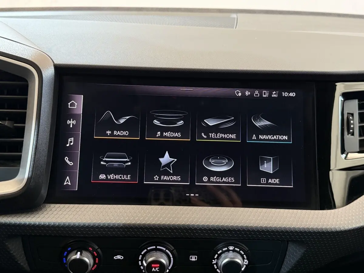Écran tactile central de l’Audi A1 2021 affichant les menus radio, médias, téléphone et navigation, tableau de bord noir.