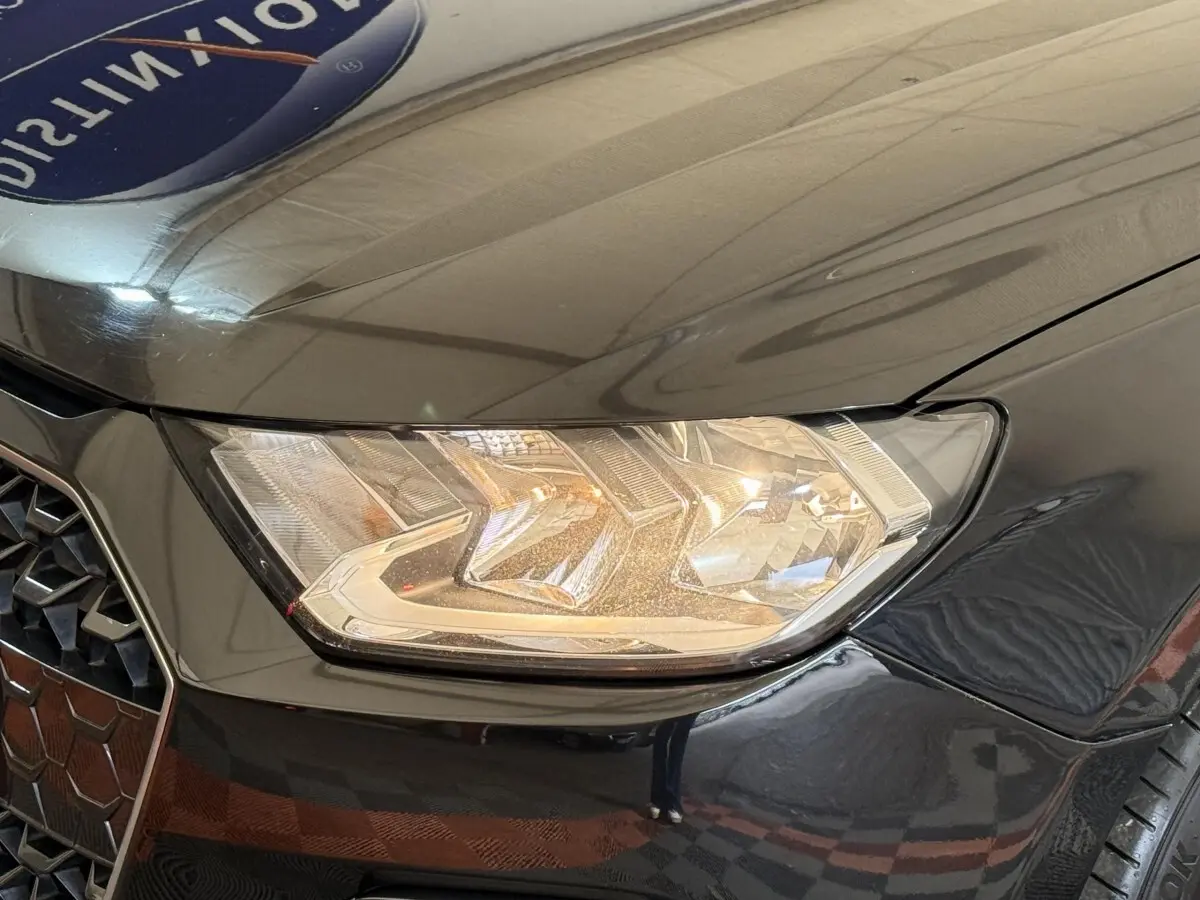 Gros plan sur le phare avant droit et la calandre noire brillante de l'Audi A1 2021 finition Business Line.