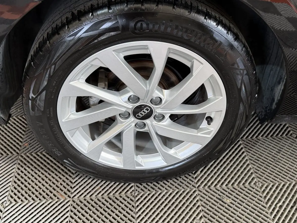 Gros plan sur la roue avant droite avec jante argentée et pneu Continental d'une Audi A1 noire.