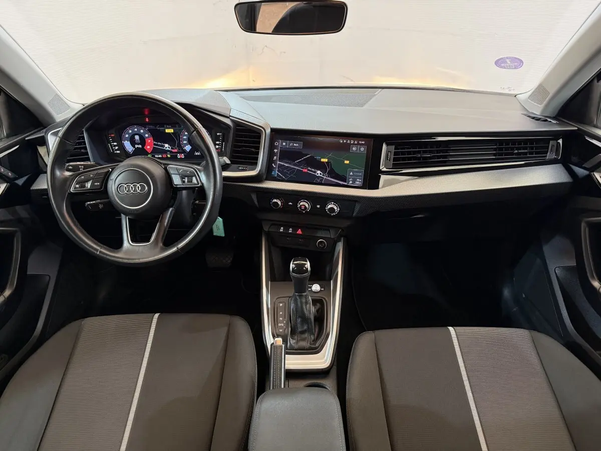 Vue intérieure avant de l'Audi A1 2021 avec volant cuir multifonctions et écran tactile de navigation.