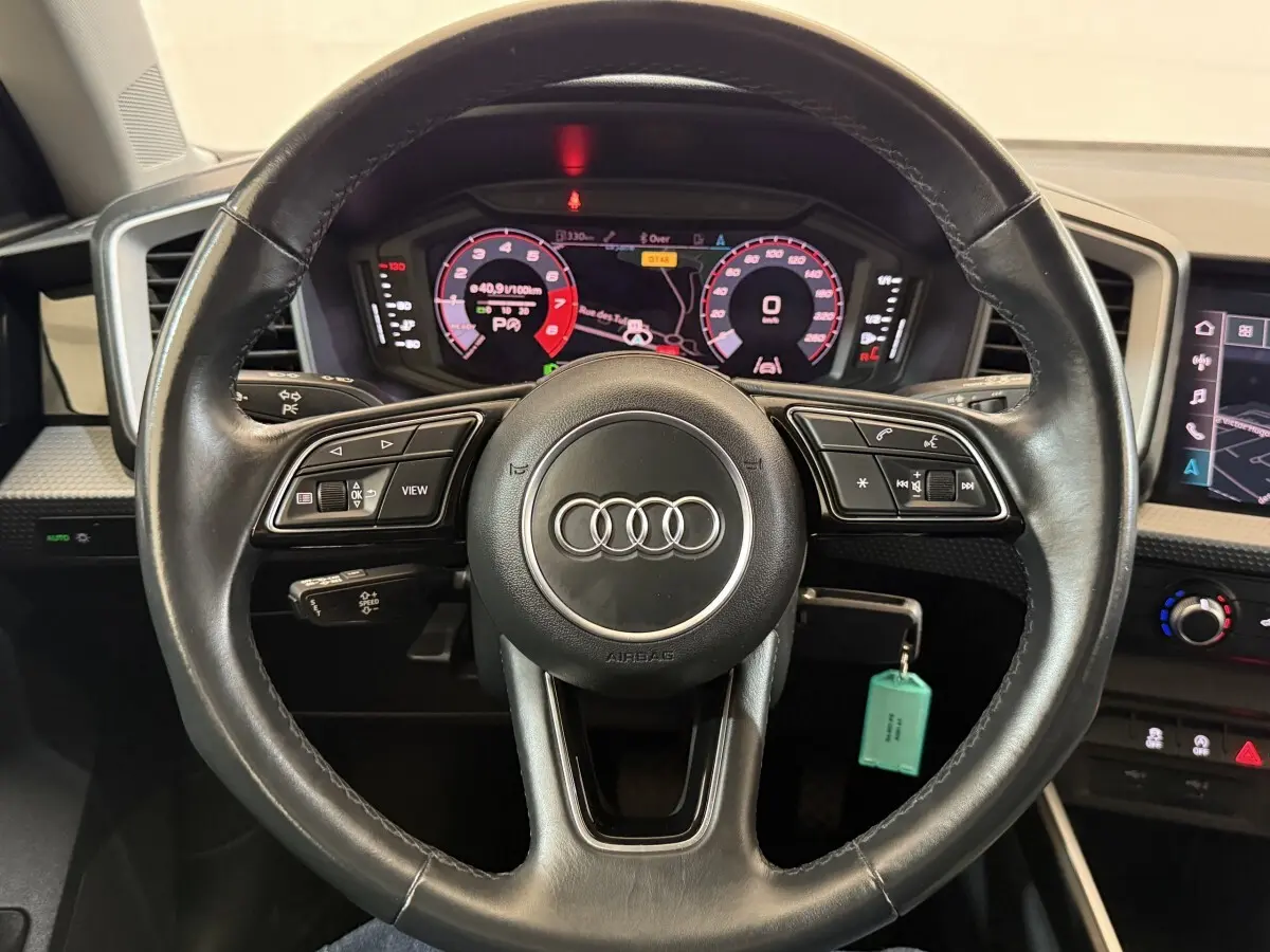 Vue rapprochée du volant cuir multifonctions noir de l'Audi A1 2021 avec tableau de bord numérique et écran tactile.