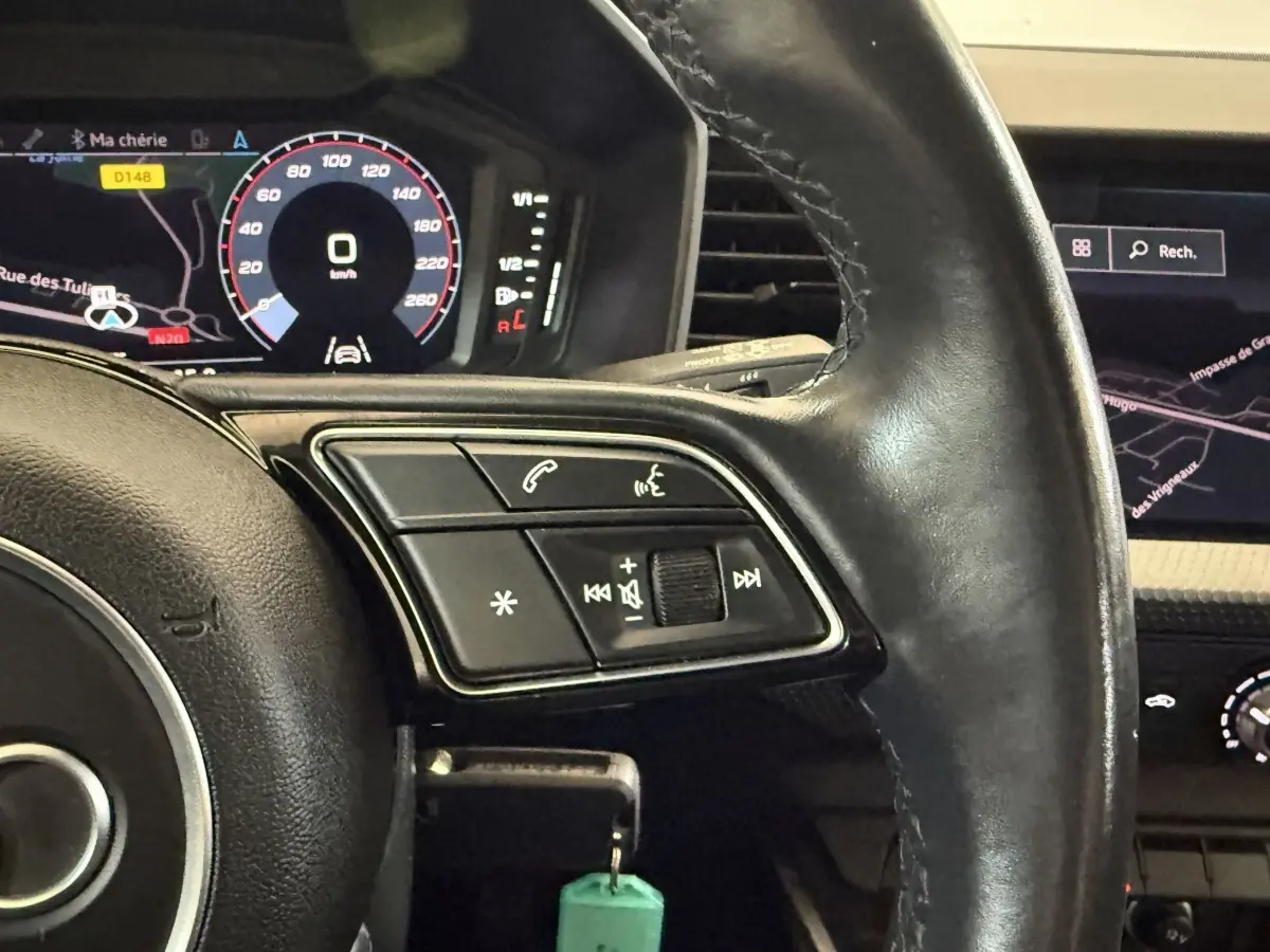 Gros plan sur le volant cuir noir multifonctions de l'Audi A1 2021 avec affichage numérique et navigation visible.