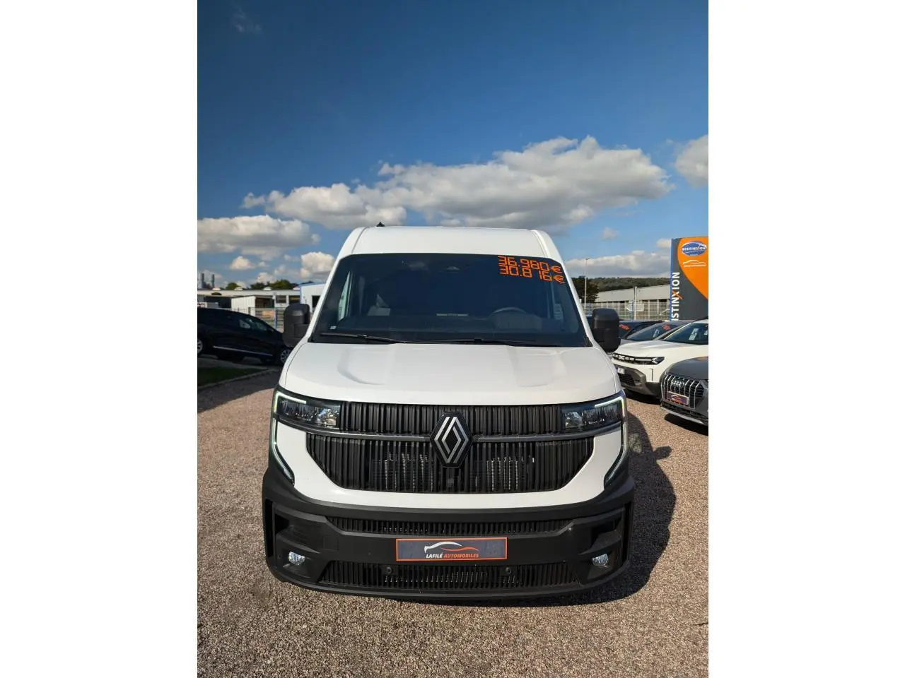 Vue frontale d'un Renault Master blanc avec calandre noire et logo Renault bien visible sous un ciel bleu.