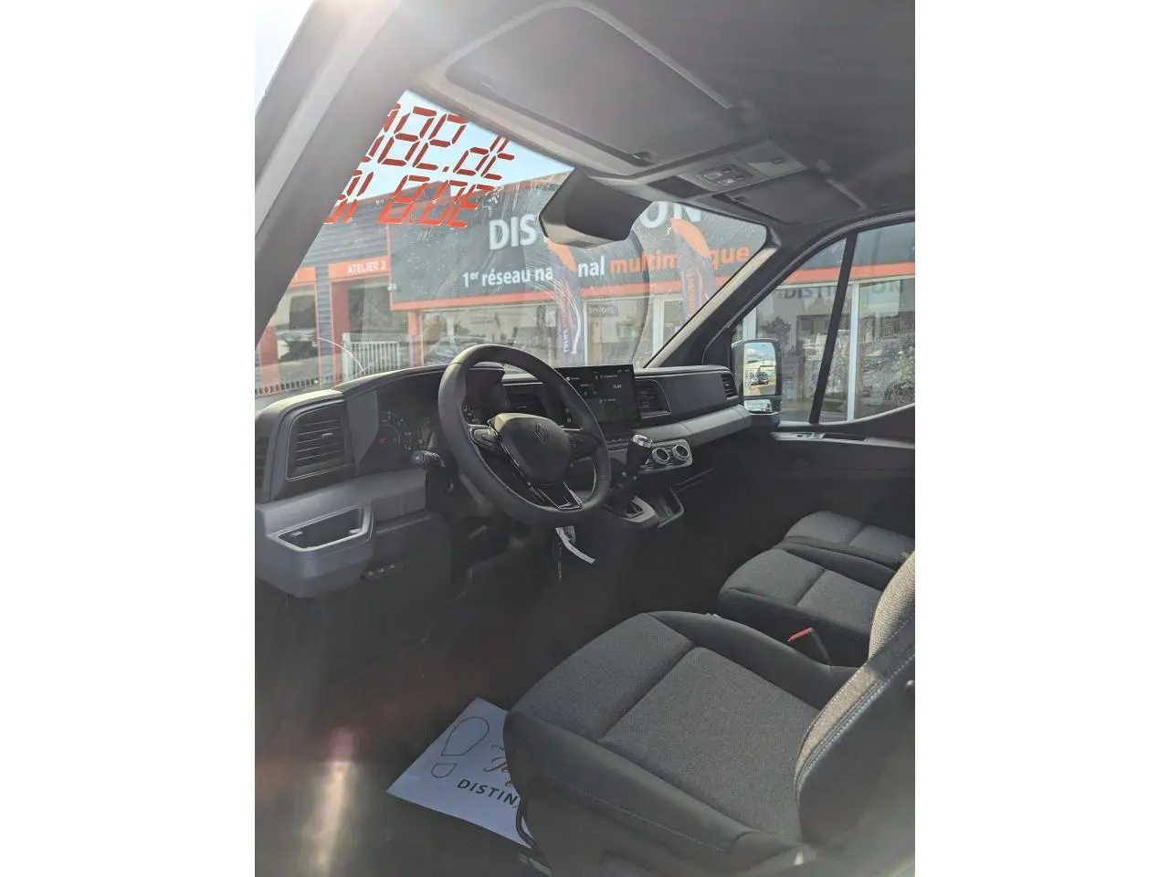 Intérieur du Renault Master 2025 vu côté conducteur, sièges gris chiné avec surpiqûres bleues et tableau de bord moderne.