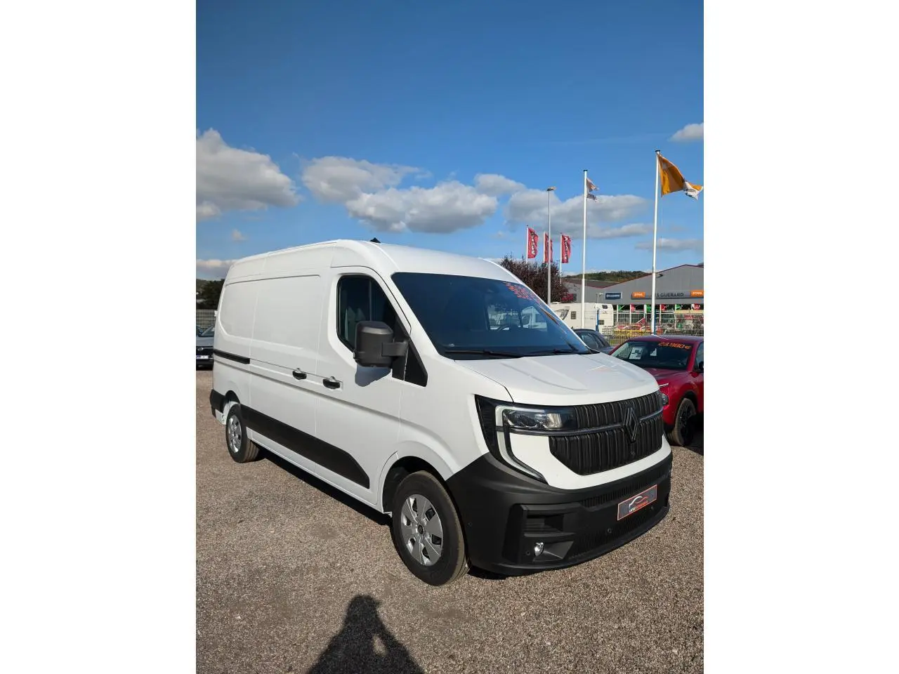 Renault Master blanc en vue 3/4 avant droit avec calandre noire et pare-chocs noir mat sur parking.
