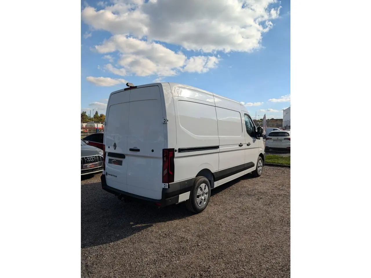 Renault Master blanc vu en 3/4 arrière droit, avec panneaux latéraux tôlés et attelage visible sous le pare-chocs.