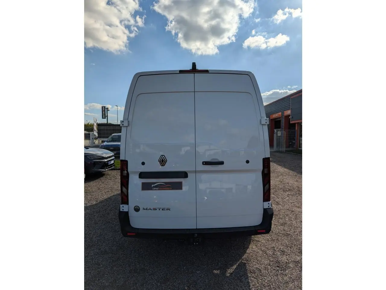Vue arrière d'un Renault Master blanc avec portes battantes, logo central et attelage visible sous le pare-chocs.