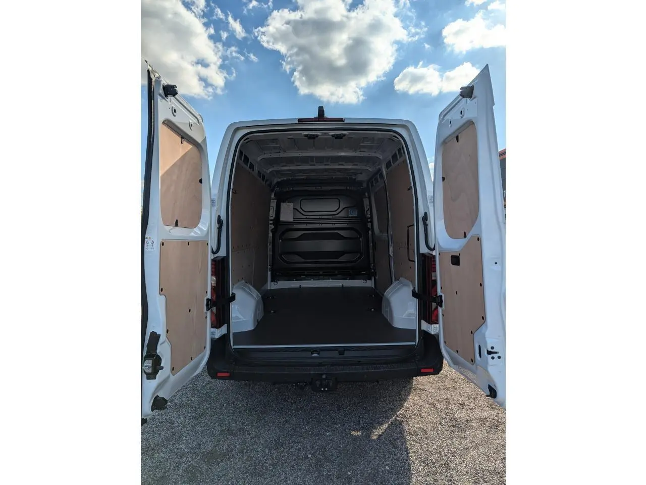 Vue arrière du Renault Master blanc 2025 avec portes ouvertes et habillage bois complet dans l'espace de chargement.