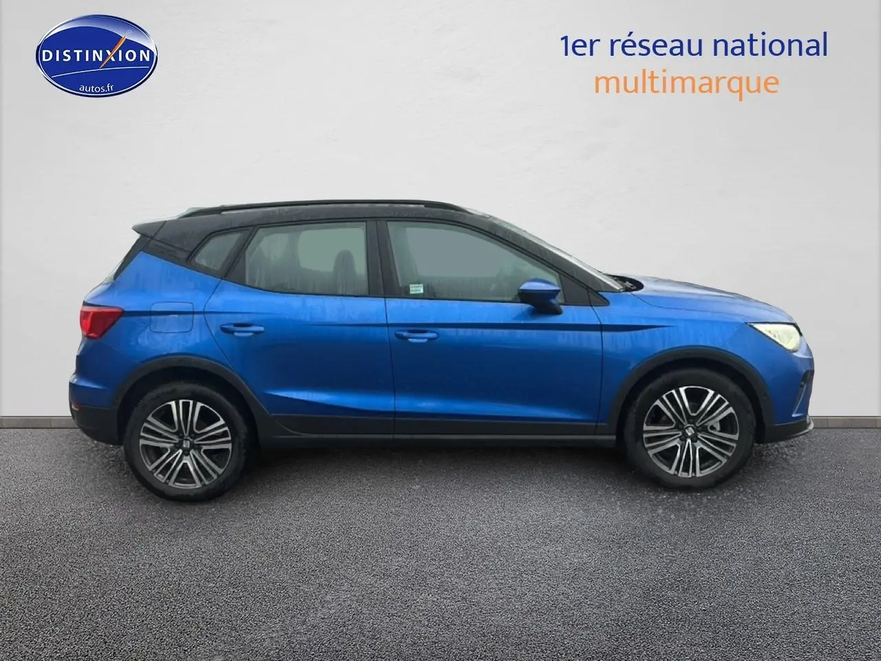 Vue de profil côté gauche d'un SEAT Arona bleu saphir avec toit noir et jantes 17 pouces urban design.