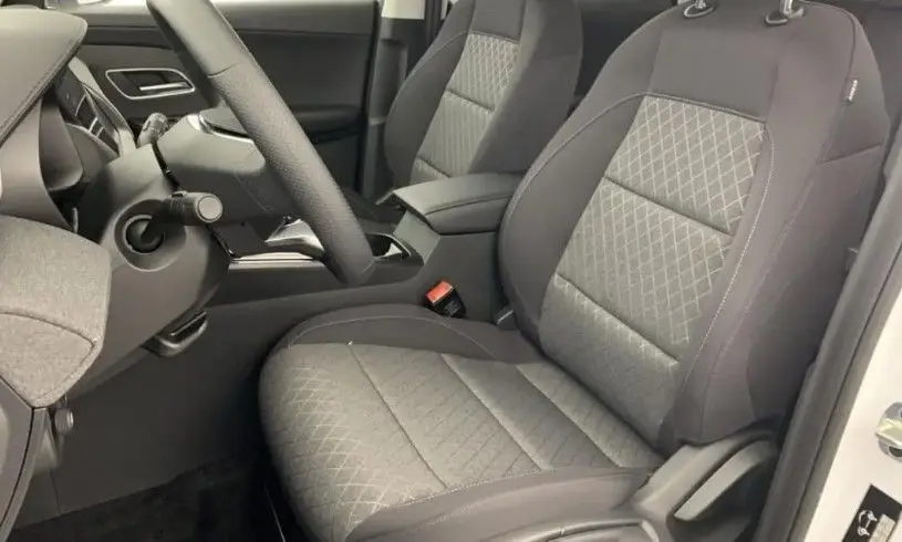 Vue intérieure du poste de conduite du MG ZS 1.5 L Hybrid+ 2025, avec volant multifonction, sièges tissu noir et écran tactile.